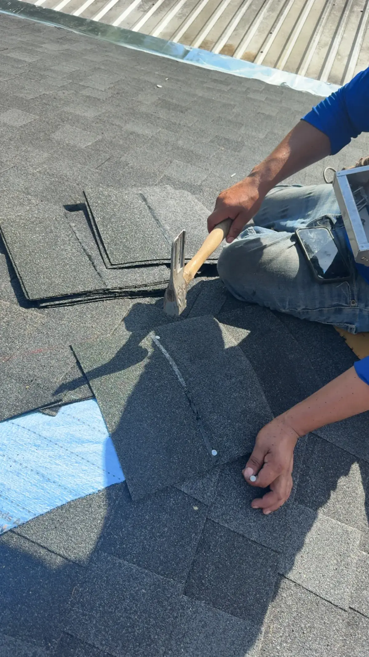 Northvale roofer hand-nailing shingles — close-up of repair work
